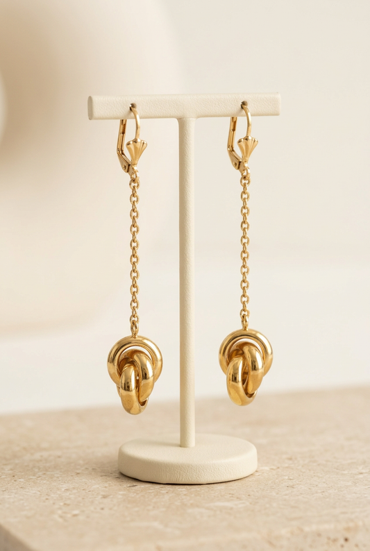 Boucles d’oreilles sur un présentoir ivoire, fond beige sable