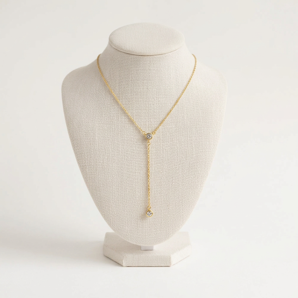 Collier en Y à deux zircons ronds sur buste ivoire, fond uni blanc cassé